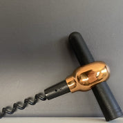 Corkscrew with black and gold handle on a gray background
