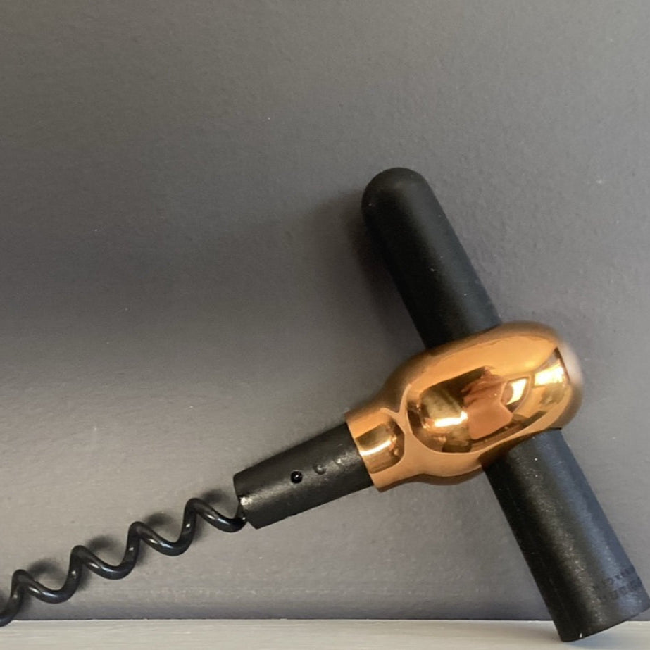 Corkscrew with black and gold handle on a gray background