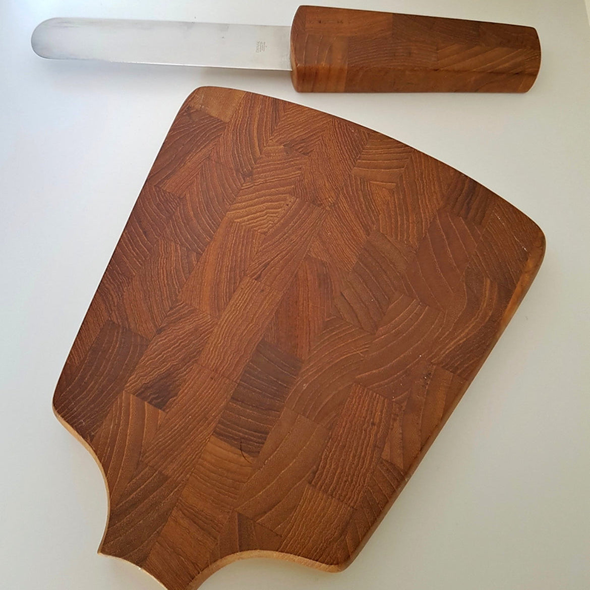 Wooden cutting board with wavy pattern and wooden-handled knife on a white background