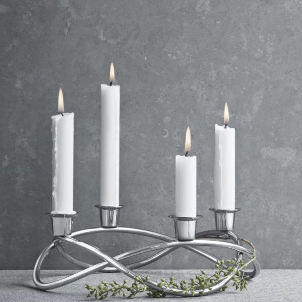 Silver candle holder with four white candles on a gray background