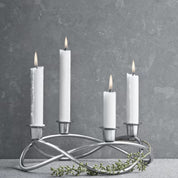 Silver candle holder with four white candles on a gray background