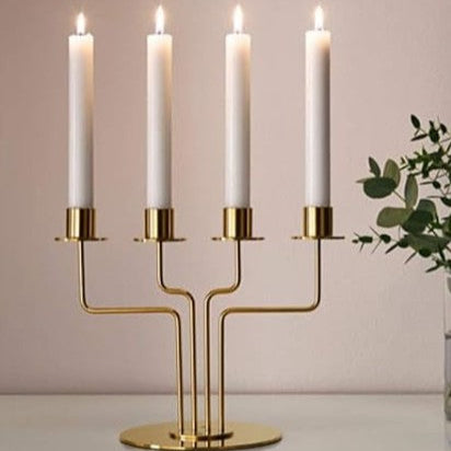 Gold candelabra with four white candles on a neutral background